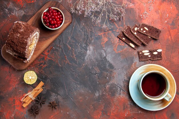 Draufsicht von Keksröllchen mit Tasse Tee auf dunkler Oberfläche