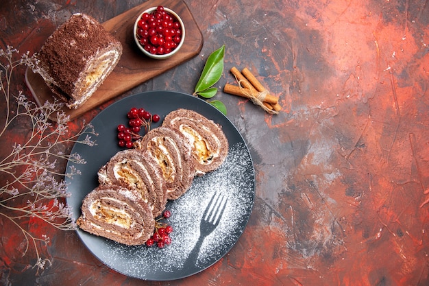 Kostenloses Foto draufsicht von keksrollenscheiben mit früchten auf dunkler oberfläche