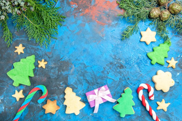 Draufsicht von kleinen Baumfiguren mit Geschenken auf einer blauen Oberfläche