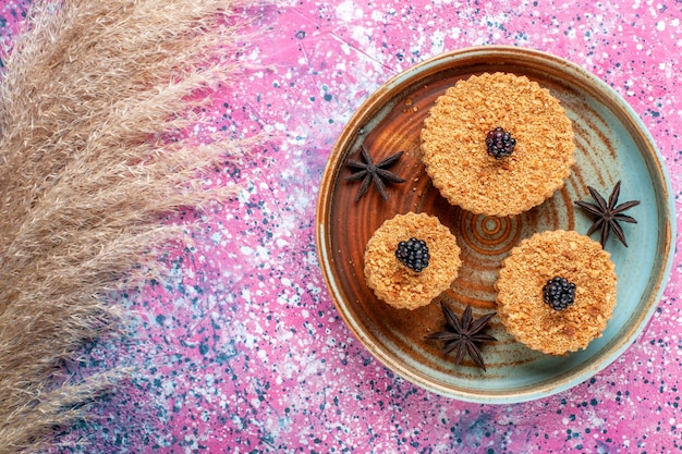 Draufsicht von kleinen leckeren Kuchen süß und köstlich Innenplatte auf rosa Oberfläche