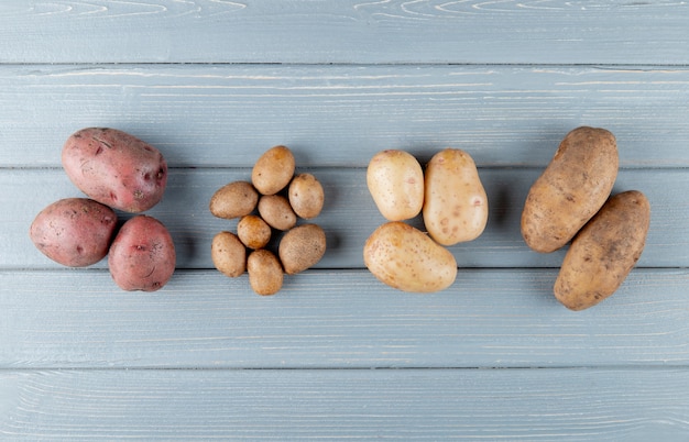 Kostenloses Foto draufsicht von kleinen und großen kartoffeln auf hölzernem hintergrund mit kopienraum