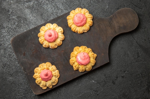 Draufsicht von kleinen Zuckerkeksen mit Erdbeercreme auf der grauen Oberfläche