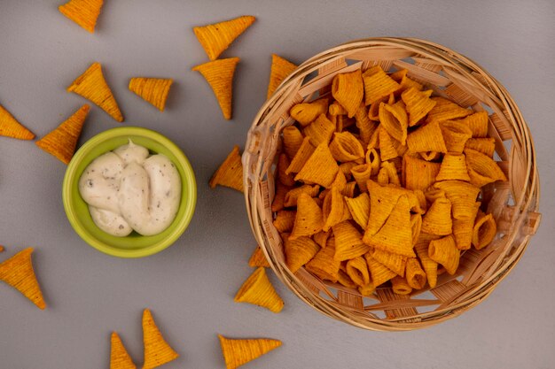 Draufsicht von knusprigen kegelförmigen gebratenen maissnacks auf einem eimer mit soße