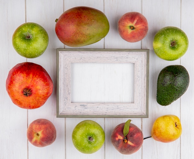 Draufsicht von köstlichen Früchten wie Granatapfel-Apfel-Mango-Birnen-Pfirsich lokalisiert auf Weiß mit Kopienraum