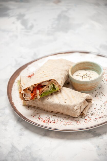 Draufsicht von Lavash Wraps und Joghurt in einer kleinen Schüssel auf einem Teller auf befleckter weißer Oberfläche