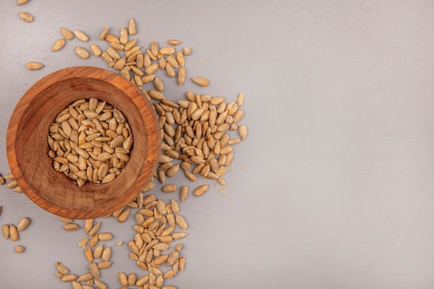 Draufsicht von leckeren geschälten Sonnenblumenkernen auf einer Holzschale mit geschälten Samen, die mit Kopienraum isoliert werden