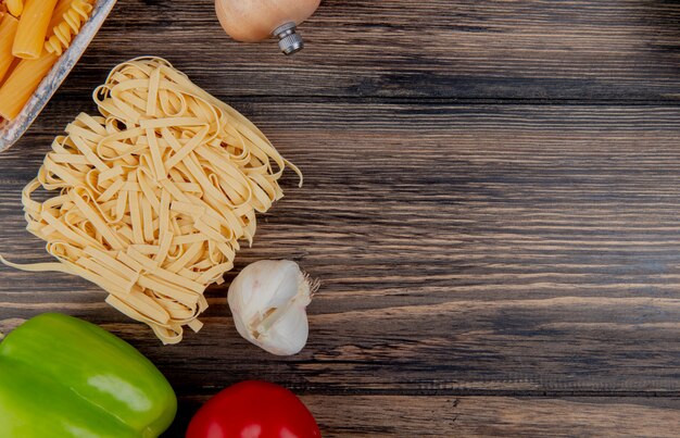 Draufsicht von Makkaronis als Tagliatelle ziti mit Pfeffer-Knoblauch-Tomate auf Holz mit Kopienraum