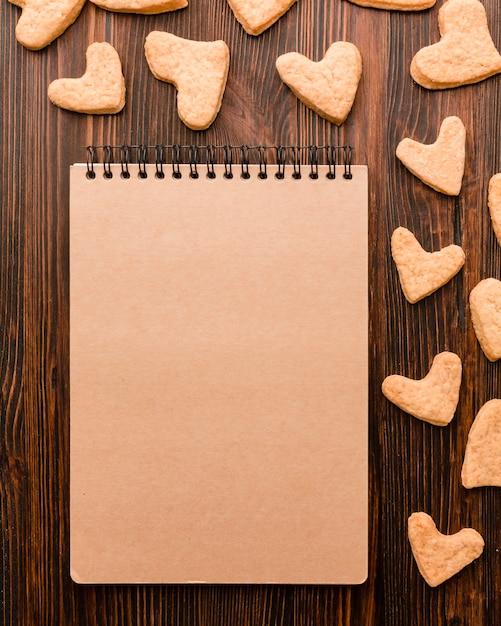 Draufsicht von Notizbuch- und Herz-förmigen Valentinstagplätzchen