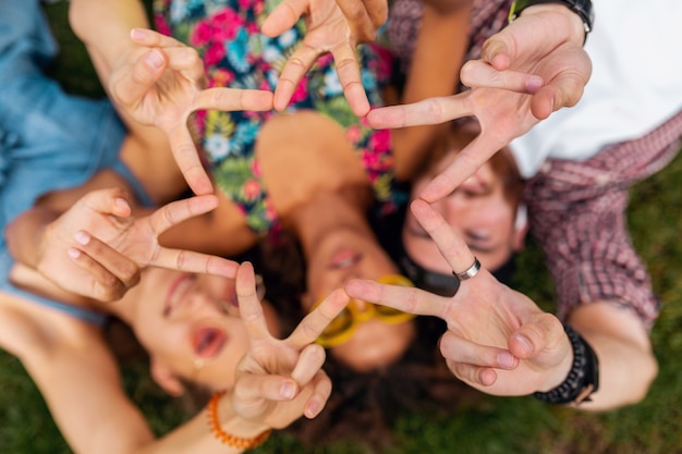 Draufsicht von oben auf bunte stilvolle glückliche junge Gesellschaft von Freunden, die auf Gras im Park liegen, Mann und Frauen, die Spaß zusammen haben