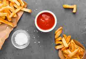 Kostenloses Foto draufsicht von pommes frites auf papier mit salz und ketchup