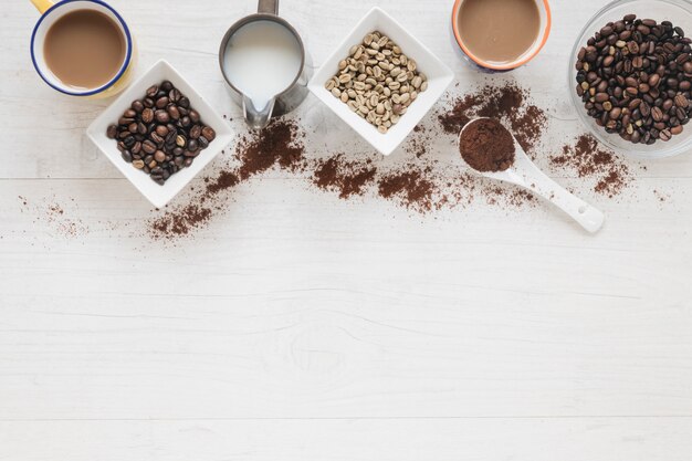 Draufsicht von rohen und gerösteten Kaffeebohnen mit Kaffeetasse auf Holztisch