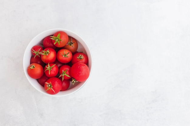 Draufsicht von roten Tomaten in der weißen Schüssel auf weißem Hintergrund