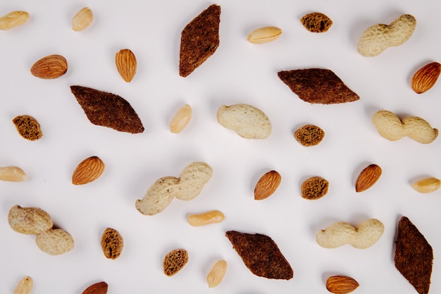 Draufsicht von Snacks Mandelerdnüssen mit Schale und ohne Schale und würzigen Brotcrackern auf Weiß