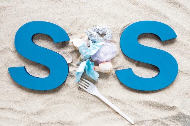 Kostenloses Foto draufsicht von sos auf strandsand mit plastik und muscheln