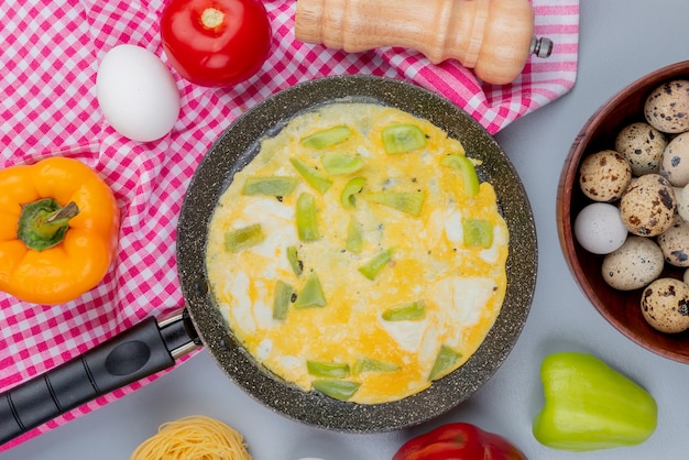 Kostenloses Foto draufsicht von spiegeleiern auf einer bratpfanne mit grünem pfeffer mit wachteleiern auf einer holzschale auf weißem hintergrund