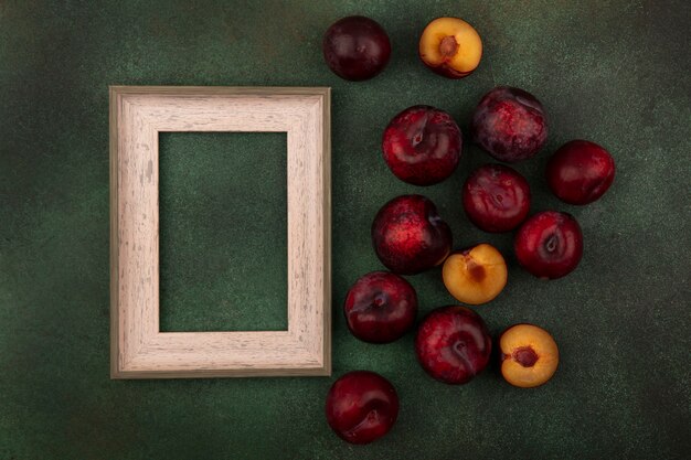 Draufsicht von süßen dunkelrothäutigen Pluots lokalisiert auf einem grünen Hintergrund mit Kopienraum