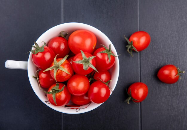 Draufsicht von Tomaten in der Tasse und auf schwarzer Oberfläche