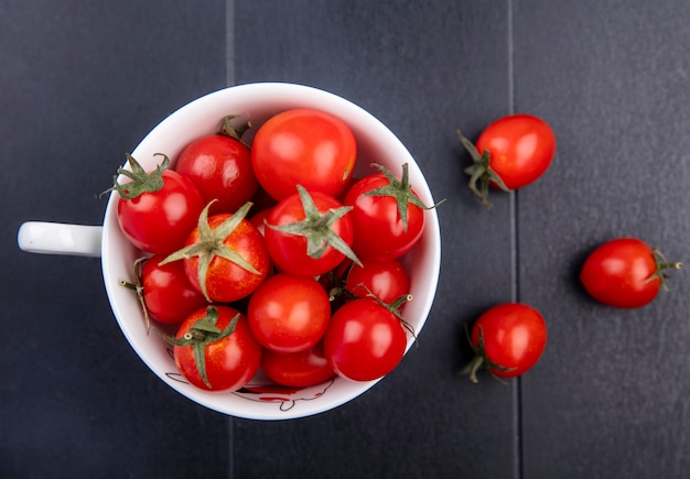 Draufsicht von Tomaten in der Tasse und auf schwarzer Oberfläche