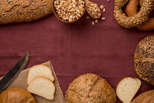 Draufsicht von verschiedenen Arten von Brot als Cob White Baguette White mit Hühneraugen und Messer auf Burgunder Hintergrund mit Kopienraum