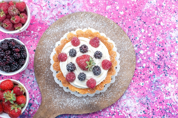 Draufsicht von verschiedenen frischen Beeren innerhalb der weißen Tassen mit Kuchen auf Licht, Beerenfrucht frisch sauer