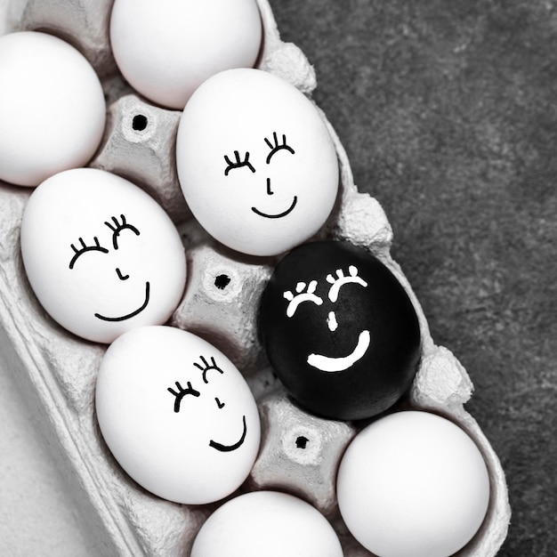 Draufsicht von vielen verschiedenfarbigen Eiern mit Gesichtern für Bewegung der schwarzen Lebensmaterie