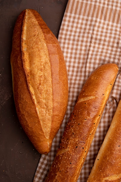 Draufsicht von vietnamesischen und französischen Baguettes auf Stoff auf kastanienbraunem Hintergrund