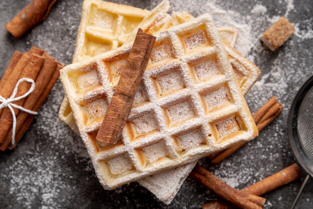 Draufsicht von Waffeln mit Puderzucker und Zimtstangen