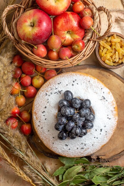 Draufsicht von weitem ein Kuchen ein Kuchen mit schwarzen Traubenkorb von Äpfeln Beeren Rosinen Ährchen