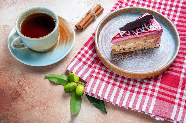 Kostenloses Foto draufsicht von weitem eine tasse tee eine tasse tee neben dem kuchen auf der karierten tischdecke