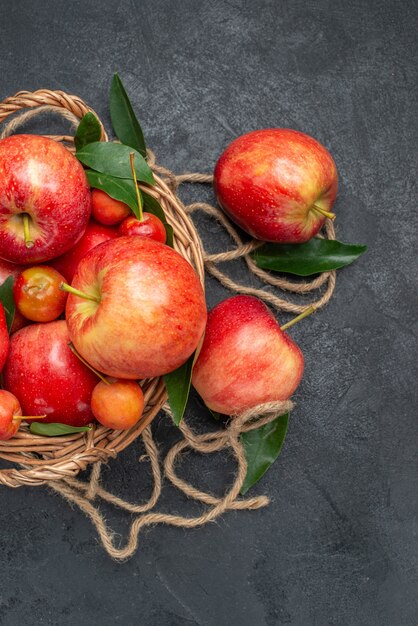 Draufsicht von weitem Fruchtkorb der appetitlichen Kirschen und Äpfel mit Blättern