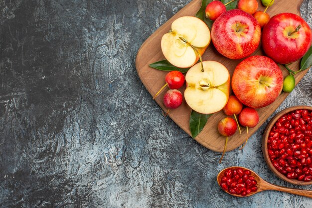 Draufsicht von weitem Äpfel Äpfel Kirschen auf dem Schneidebrett Granatapfel in der Schüssel