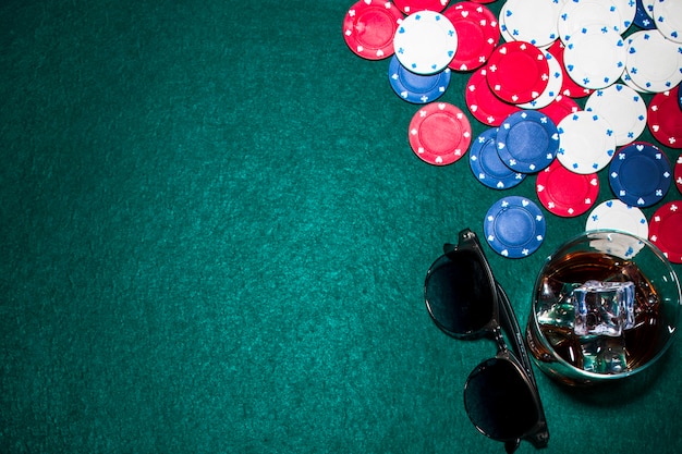 Kostenloses Foto draufsicht von whiskyglas; sonnenbrille und casino-chips am pokertisch