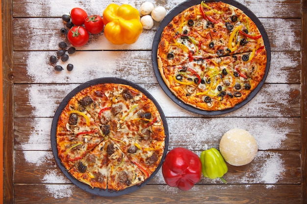 Kostenloses Foto draufsicht von zwei italienischen pizzen mit fleisch, grünem pfeffer, olive und pilz