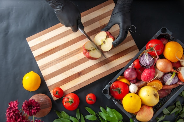 Draufsicht weiblicher Koch, der Apfel auf der dunklen Oberfläche schneidet