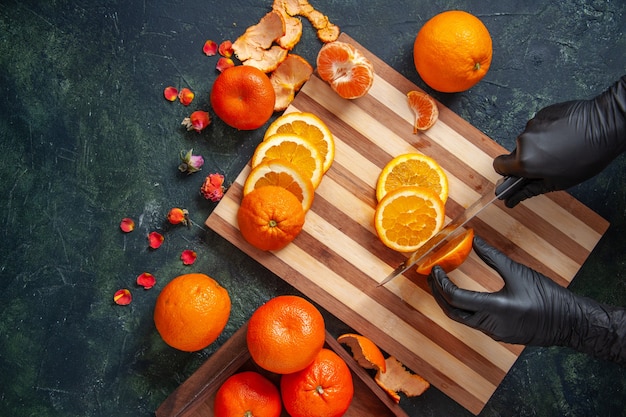 Draufsicht weiblicher Koch, der Orange auf dunkler Oberfläche schneidet