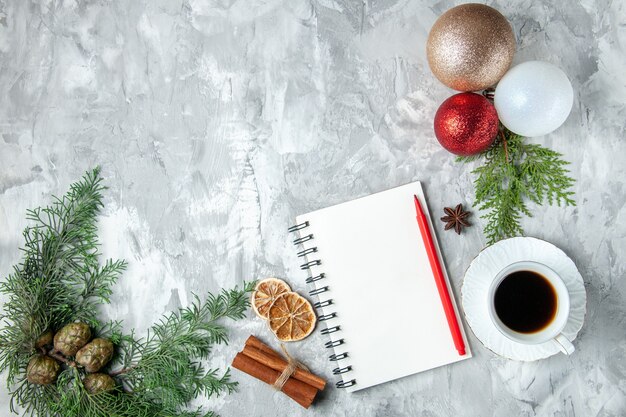Draufsicht Weihnachtsbaumkugeln Notizbuch Bleistift Zimtstangen Tasse Tee auf grauer Oberfläche