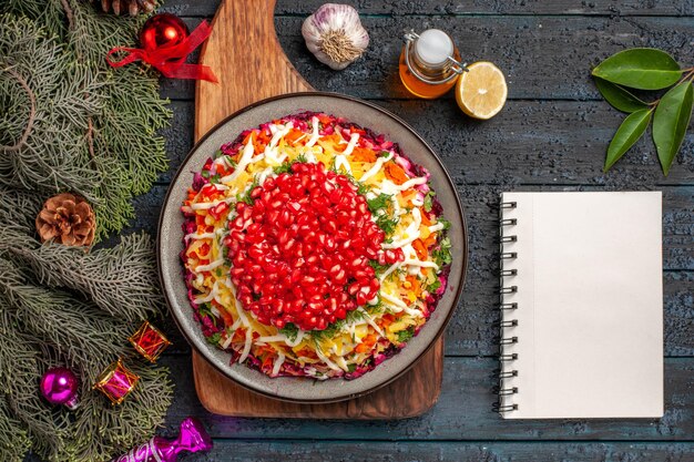 Draufsicht Weihnachtsessen auf der Tafel des Weihnachtsgerichts an Bord neben der weißen Notebook-Flasche mit Ölzweigen mit Kegelschale mit Gewürzen Knoblauch Zitrone