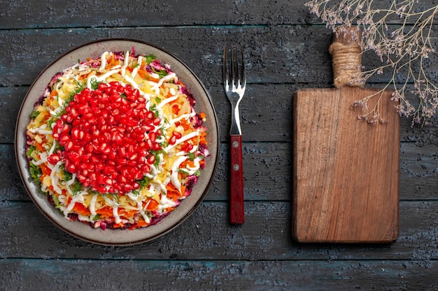 Draufsicht Weihnachtsessen leckeres Weihnachtsgericht mit Granatapfelkernen neben der Gabel und dem Schneidebrett auf dem grauen Tisch