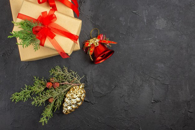 Draufsicht Weihnachtsgeschenk in braunem Papier mit rotem Band Weihnachtsbaum Ornamente auf dunkler Oberfläche gebunden