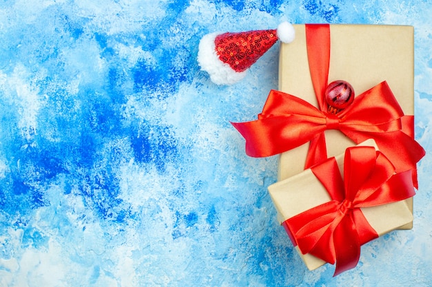 Draufsicht Weihnachtsgeschenke kleine Weihnachtsmütze auf blauem weißen Tisch freien Platz