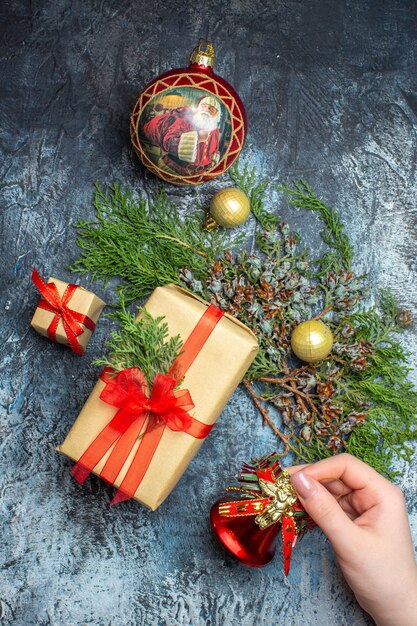 Draufsicht Weihnachtsgeschenke mit grünem Zweig auf hell-dunklem Hintergrund