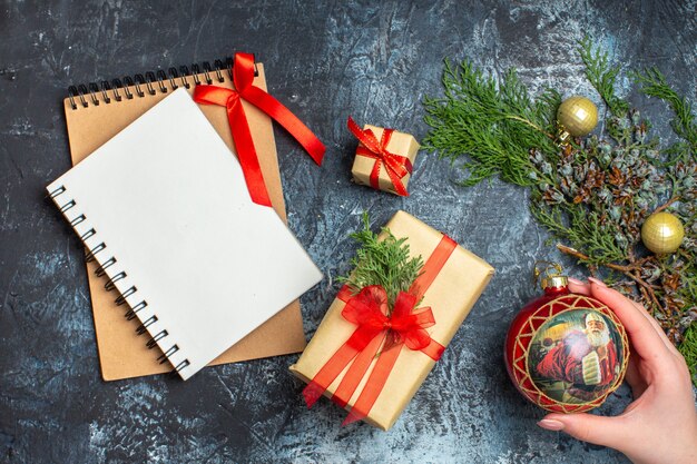 Draufsicht Weihnachtsgeschenke mit Notizblock auf hell-dunklem Hintergrund