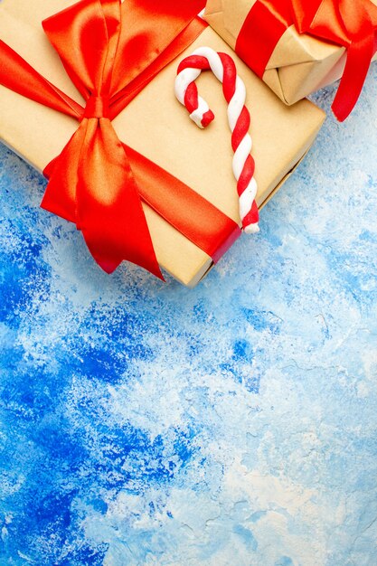 Draufsicht Weihnachtsgeschenke mit roter Schleife Weihnachtssüßigkeiten auf blauem Tisch freier Raum gebunden