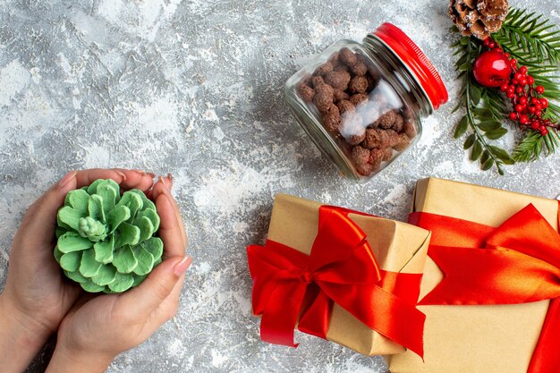 Draufsicht Weihnachtsgeschenke Müsli im Glasgrünkegel in weiblicher Hand auf grauem Tisch