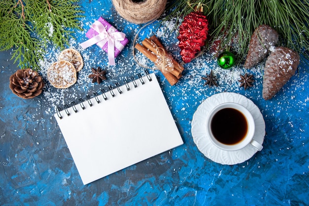 Draufsicht Weihnachtsgeschenke Tannenbaum Zweige Kegel Anis Notizbuch eine Tasse Tee auf blauem Hintergrund freier Platz