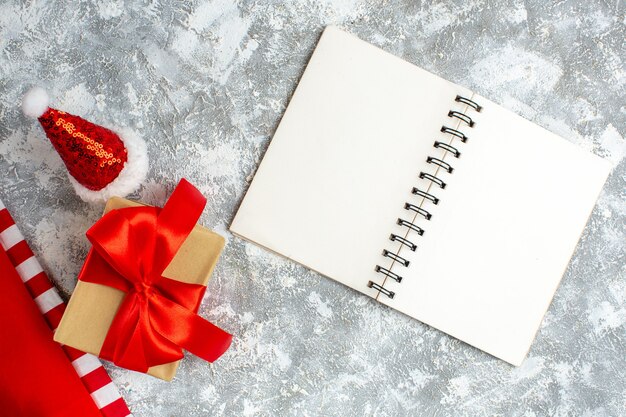 Draufsicht Weihnachtsgeschenke Weihnachtsmütze Notizbuch auf grauweißem Tisch