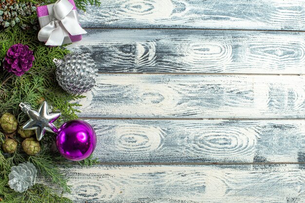 Draufsicht Weihnachtsschmuck kleines Geschenk Tannenbaum Zweige Weihnachtsspielzeug auf Holzoberfläche