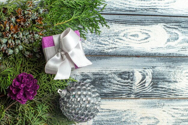 Kostenloses Foto draufsicht weihnachtsschmuck kleines geschenk tannenbaum zweige weihnachtsspielzeug auf holzuntergrund