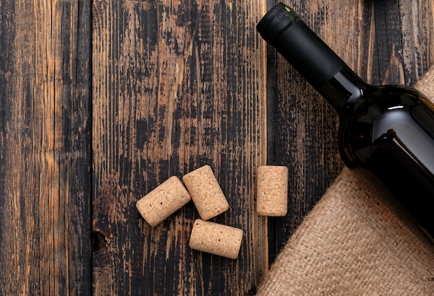 Draufsicht Weinflasche auf Sackleinen mit Kopienraum auf dunklem Holz horizontal