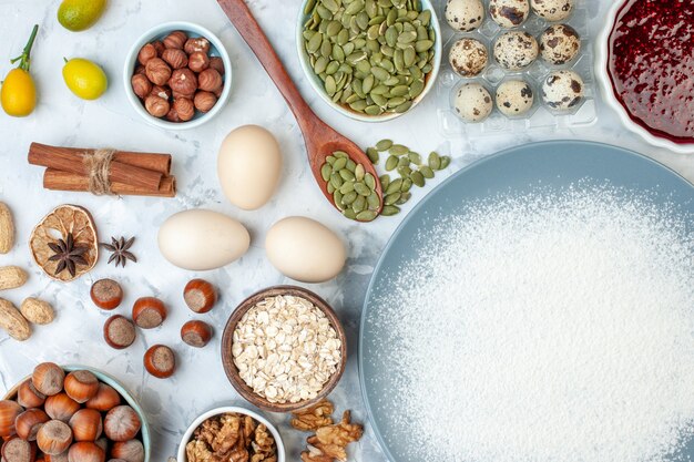 Draufsicht Weißmehl Innenplatte mit Nusssamen und Eiern auf weißem Nussteig backen Essen Foto Obstkuchen Keks Gelee